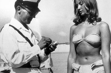 A police officer issuing a woman a ticket for wearing a bikini on beach at Rimini, Italy, 1957